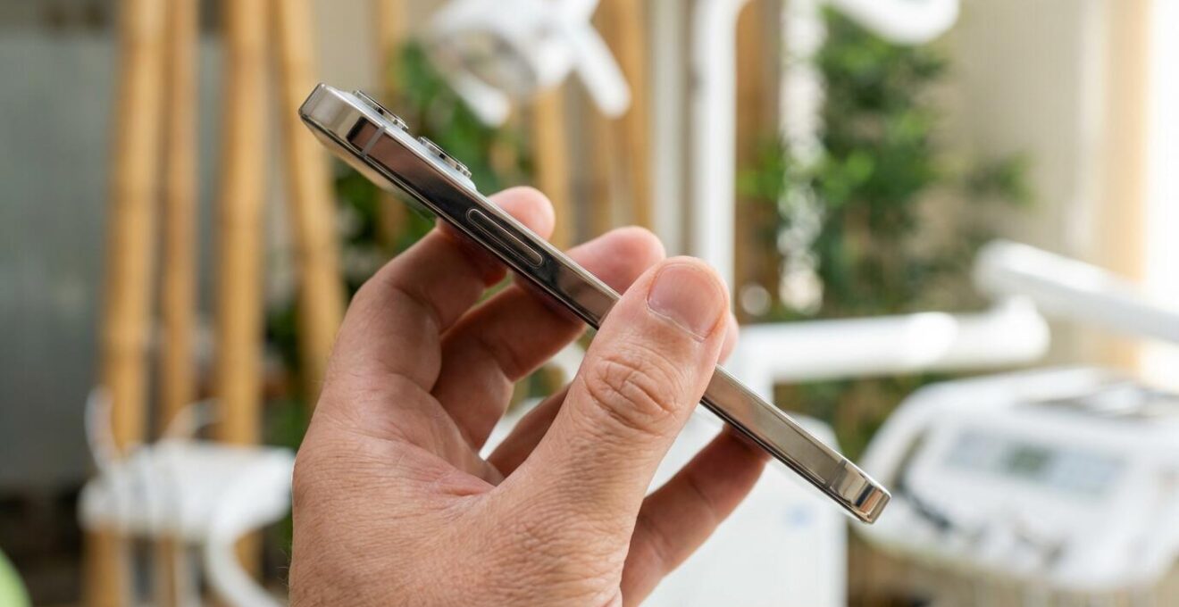 Main tenant un smartphone montrant une interface d'application santé dans un cabinet médical tropical