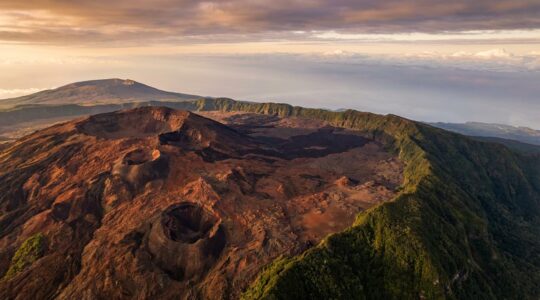 Vue aérienne du Piton de la Fournaise avec ses coulées de lave fluides et son cratère Dolomieu, illustrant la nature effusive non explosive du volcan réunionnais